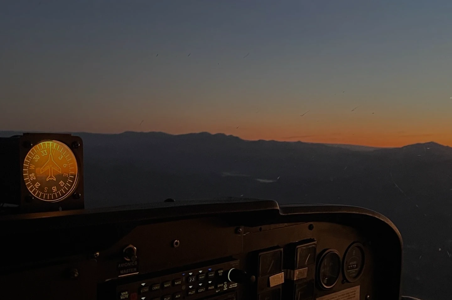 Cockpit view of a Cessna flying over Arizona mountains at sunset