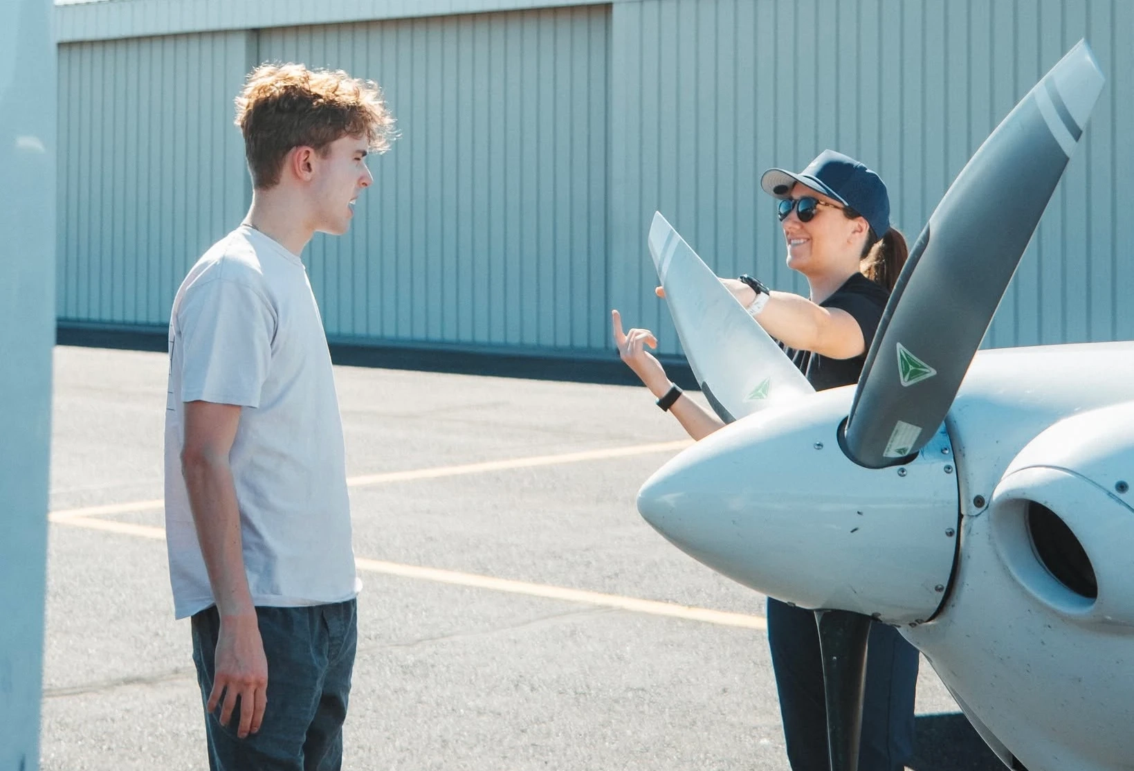 Flight instructor talking with a student pilot beside an airplane at Falcon Field