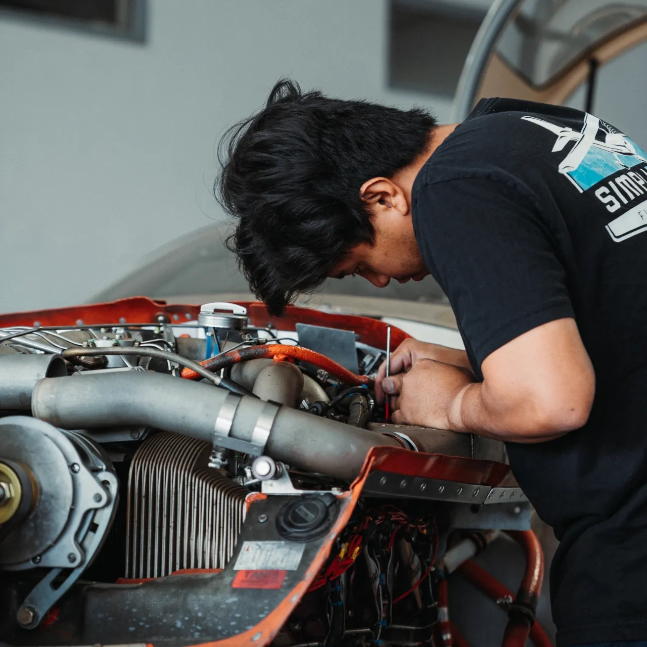 SimpliFly Flight School mechanic inspecting an aircraft engine in the hangar
