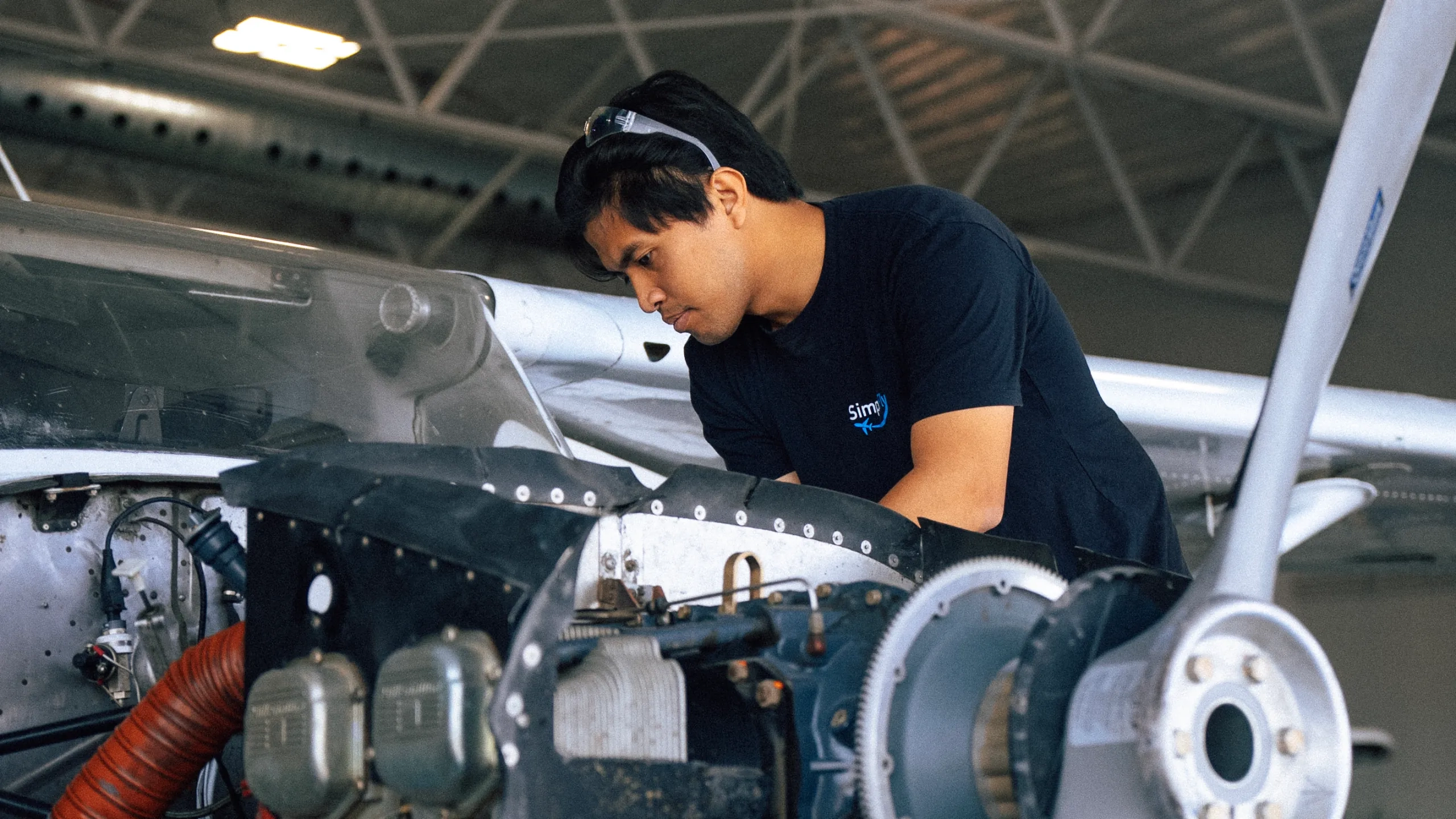 SimpliFly Mechanic servicing airplane engine behind propeller