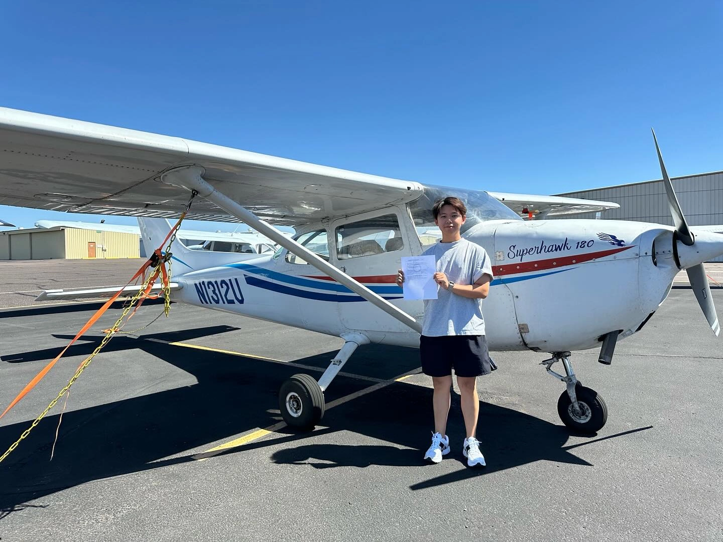 Student beside airplane holding certificate