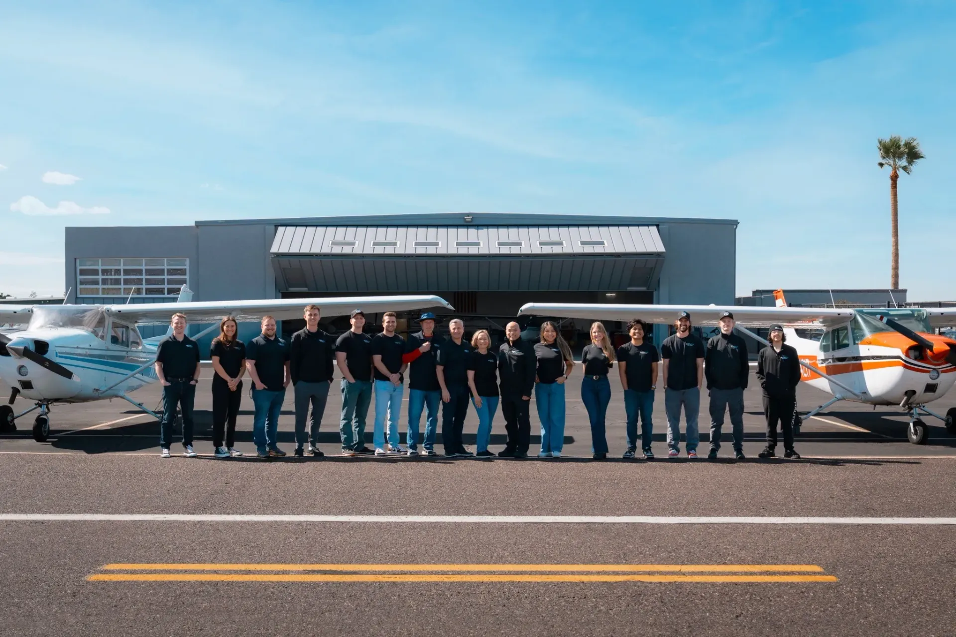 SimpliFly's team posing in front of their aircraft and airport hangar in Mesa, Arizona